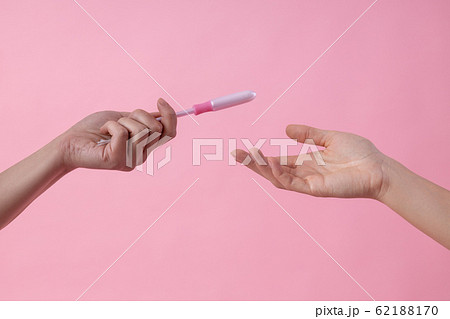 Girl giving tampon in applicator to her friend stock photo 62188170