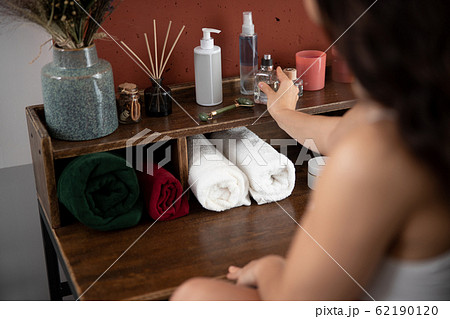 Young woman putting bottle of perfume on shelf 62190120