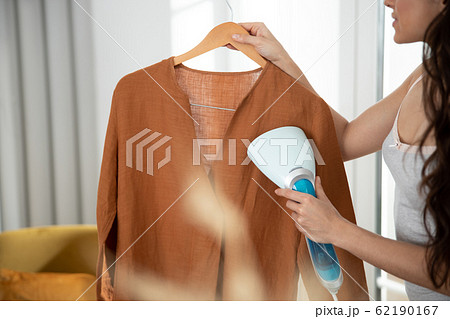 Young lady refreshing shirt with clothes steamer Young lady refreshing shirt with clothes steamer 62190167