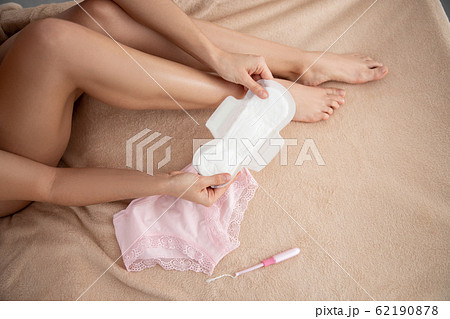 Young woman holding white menstrual sanitary napkin 62190878