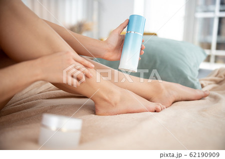 Lady holding cosmetic cream and touching leg 62190909