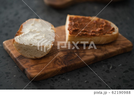 Toasted half of ciabatta with cream cheese and red pesto on olive board 62190988