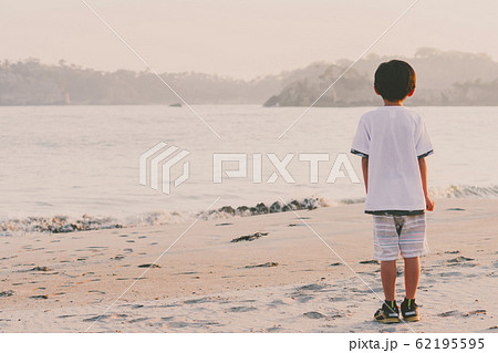 男の子 後ろ姿 フィルム調 海 見つめるの写真素材