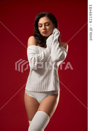 Sensual model posing in sweater and underwear. Sensual model posing in sweater and underwear. 62199483