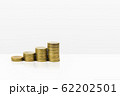 Growing stacked of coins on white table and 62202501