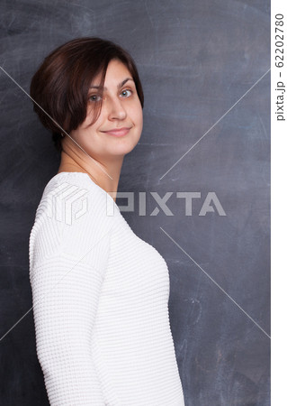 Attractive woman stands sideways and smiling 62202780