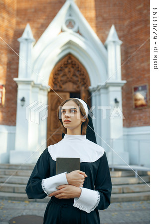 Young nun in a cassock, church on background 62203193