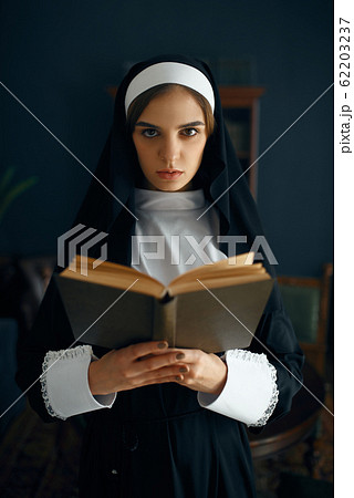 Young nun in a cassock reads a prayer 62203237