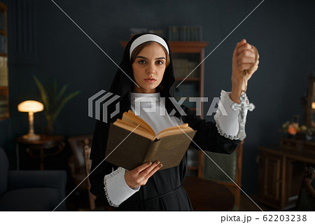 Young nun in a cassock holds book 62203238