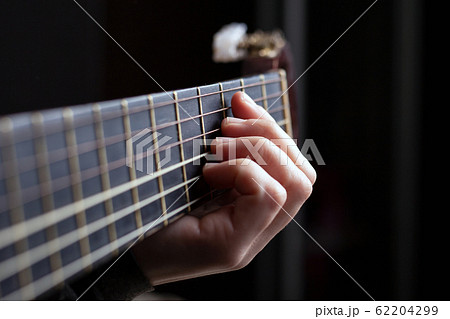 Female hand clamps a chord on an acoustic guitar Female hand clamps a chord on an acoustic guitar 62204299