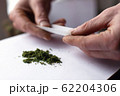 make a roll of cannabis herb. hemp roll closeup 62204306