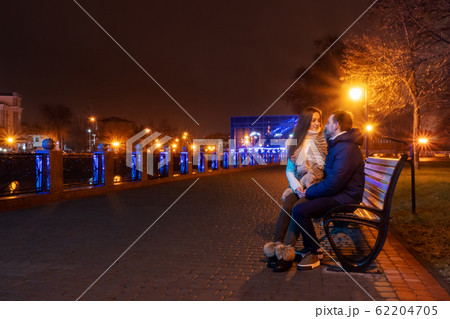 couple sitting on a bench at night 62204705