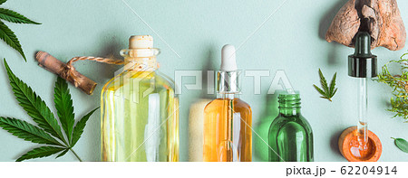 Glass bottles with CBD oil, THC tincture and hemp leaves on blue background. Flat lay, minimalism. Cosmetics CBD hemp oil. Glass bottles with CBD oil, THC tincture and hemp leaves on blue background. Flat lay, minimalism. Cosmetics CBD hemp oil. 62204914