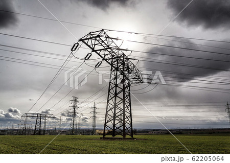 Sun hidden behind dramatic clouds and electricity pylons conducting current from distribution power station, solar renewable energy and grid stability concept, copy space Sun hidden behind dramatic clouds and electricity pylons conducting current from distribution power station, solar renewable energy and grid stability concept, copy space 62205064