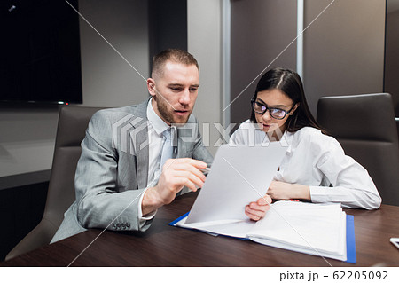Manager sitting at desk, secretary bringing contract to sign. 62205092