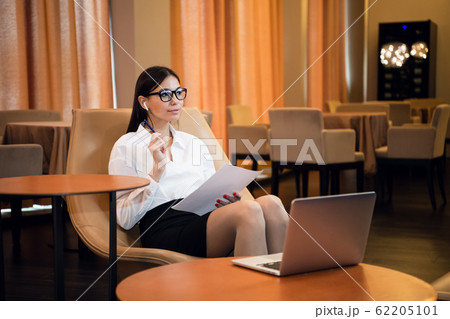 Portrait of businesswoman with laptop writes on a document at cafe Portrait of businesswoman with laptop writes on a document at cafe 62205101