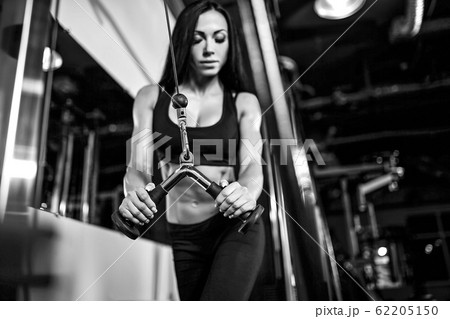 woman flexing muscles on cable machine in gym. exercise on triceps woman flexing muscles on cable machine in gym. exercise on triceps 62205150