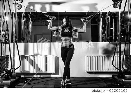 woman flexing muscles on cable machine in gym. exercise on biceps woman flexing muscles on cable machine in gym. exercise on biceps 62205165