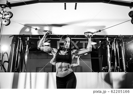 woman flexing muscles on cable machine in gym. exercise on biceps 62205166
