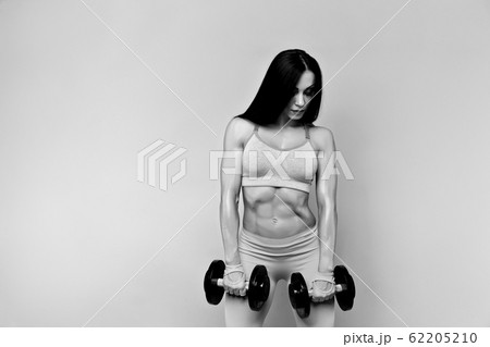 Muscular woman working out with dumbbells. Isolated. Gray 62205210