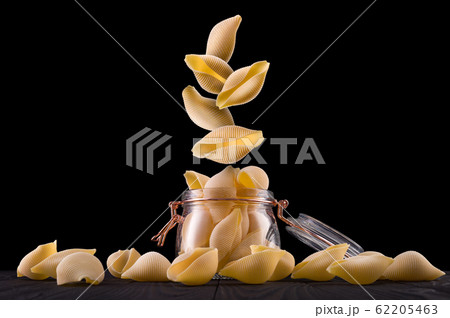 Jar of conchiglie pasta shell on wooden table isolated on black background 62205463