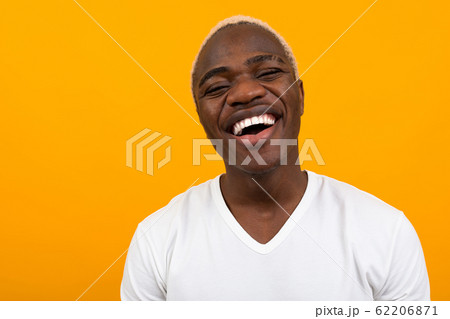 Closeup portrait of a smiling handsome black blond African man on an orange background with copy Closeup portrait of a smiling handsome black blond African man on an orange background with copy 62206871