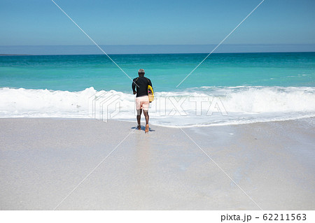 Old man with a surfboard at the beach 62211563