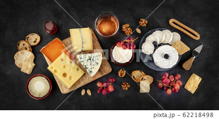 Cheese variety panorama with wine and fruit, a flat lay, overhead shot on a black background 62218498