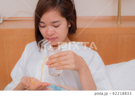 ベットで薬を飲む若い女性 62218833