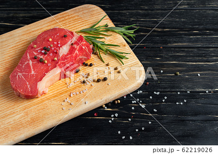 one pieces of juicy raw beef on a cutting board on 62219026
