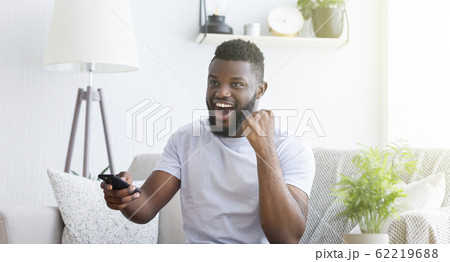 Emotional african soccer fan watching football on tv at home 62219688