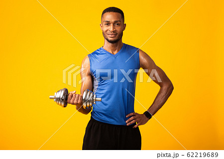 African bodybuilder pumping up biceps with dumbbells 62219689