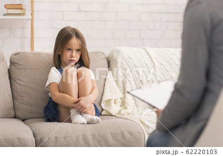 Concerned Little Girl Sitting Alone At Therapy Session With Children Psychologist 62220103