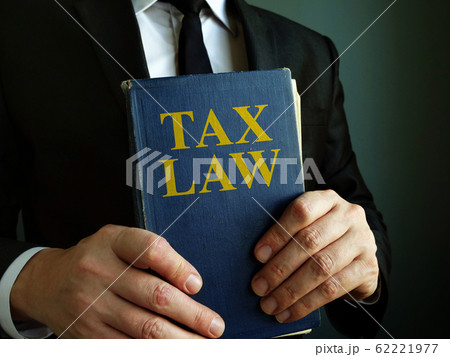 Accountant holds tax law book. Accountant holds tax law book. 62221977
