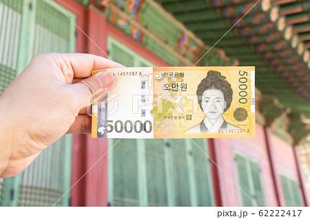 Traveller hand hold 50000 korean won banknote on defocused Korean palace background. 62222417