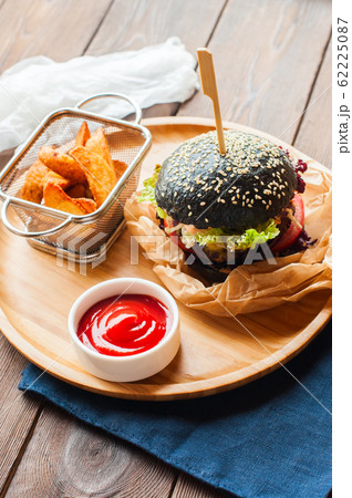 Black burger with french fries and ketchup in a 62225087