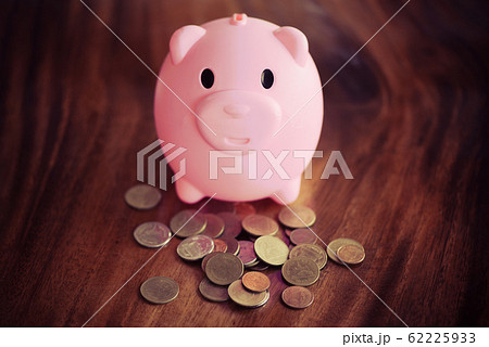 Money coin and pink piggy bank at table at home Money coin and pink piggy bank at table at home 62225933