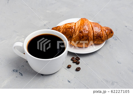 Coffee cup and croissant on gray stone background. Perfect breakfast in the morning. Rustic style, top view, food banner, selective focus Coffee cup and croissant on gray stone background. Perfect breakfast in the morning. Rustic style, top view, food banner, selective focus 62227105