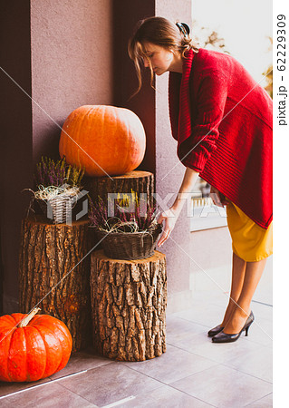 Designer decorates patio with heather flowers and orange pumpkins for autumn holidays 62229309