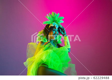 Beautiful young woman in carnival and masquerade costume on gradient studio background in neon light Beautiful young woman in carnival and masquerade costume on gradient studio background in neon light 62229488