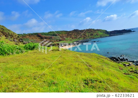 A corner of the island with green grass, blue water and sky 62233621