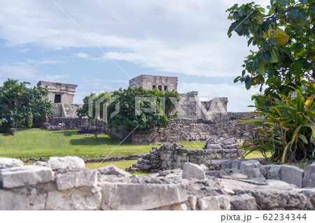 Ruins of ancient Tulum. Architecture of ancient maya. View with temple and other old buildings, houses. Blue sky and lush greenery of nature. travel photo. Wallpaper or background. Yucatan. Ruins of ancient Tulum. Architecture of ancient maya. View with temple and other old buildings, houses. Blue sky and lush greenery of nature. travel photo. Wallpaper or background. Yucatan. 62234344