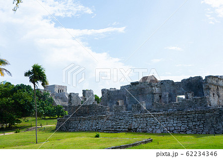 Ruins of ancient Tulum. Architecture of ancient maya. View with temple and other old buildings, houses. Blue sky and lush greenery of nature. travel photo. Wallpaper or background. Yucatan. Ruins of ancient Tulum. Architecture of ancient maya. View with temple and other old buildings, houses. Blue sky and lush greenery of nature. travel photo. Wallpaper or background. Yucatan. 62234346