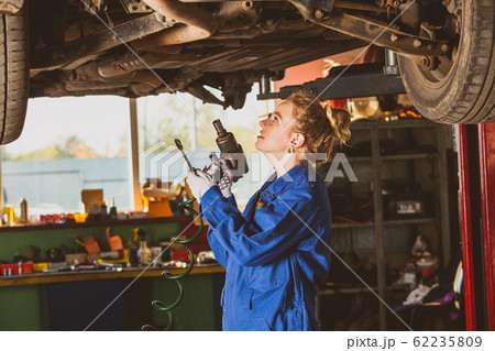 Young female mechanic works under the car Young female mechanic works under the car 62235809