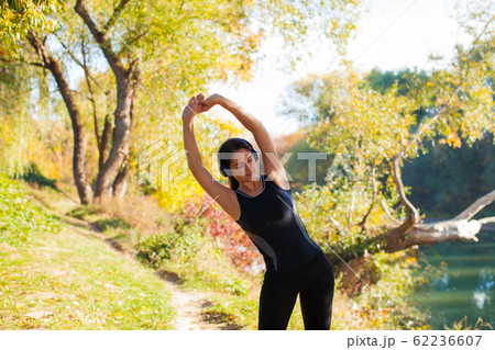 Runner woman stretching arms before run in morning time 62236607