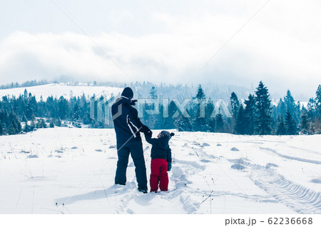 Back view of little boy with father during ski holiday 62236668