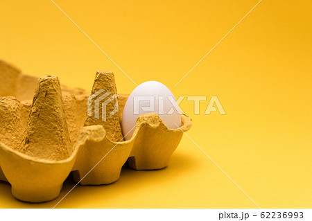 one egg inside of a six pack cardboard on yellow background. concept designs one egg inside of a six pack cardboard on yellow background. concept designs 62236993