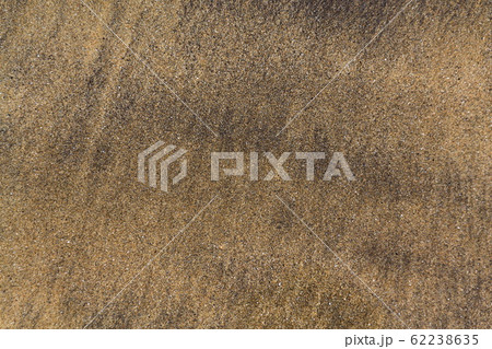 Waves coming and leaving wet sand on sea shore, brown yellow and black grains from volcanic ash, zen background, harmony and meditation concept, flat lay top view, copy space 62238635