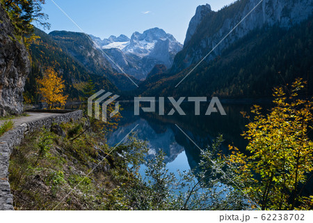 Peaceful autumn Alps mountain lake with clear transparent water and reflections. Gosauseen or Vorderer Gosausee lake, Upper Austria. Dachstein summit and glacier in far. Peaceful autumn Alps mountain lake with clear transparent water and reflections. Gosauseen or Vorderer Gosausee lake, Upper Austria. Dachstein summit and glacier in far. 62238702