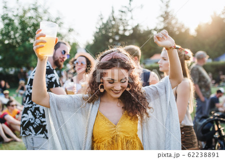 A young woman with drink dancing at summer festival. A young woman with drink dancing at summer festival. 62238891